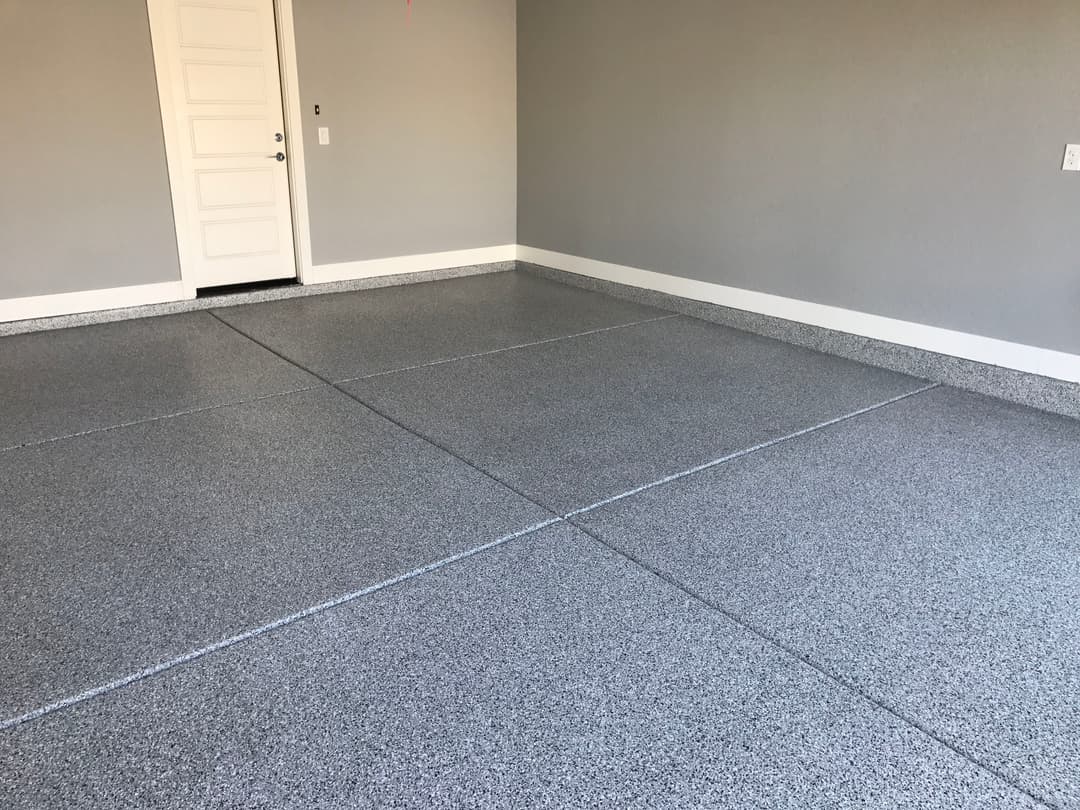 Modern garage interior with a clean, gray epoxied floor and white door.