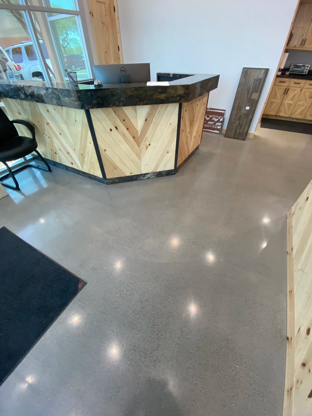 Modern reception area featuring a wooden counter and polished concrete floor with bright lighting.