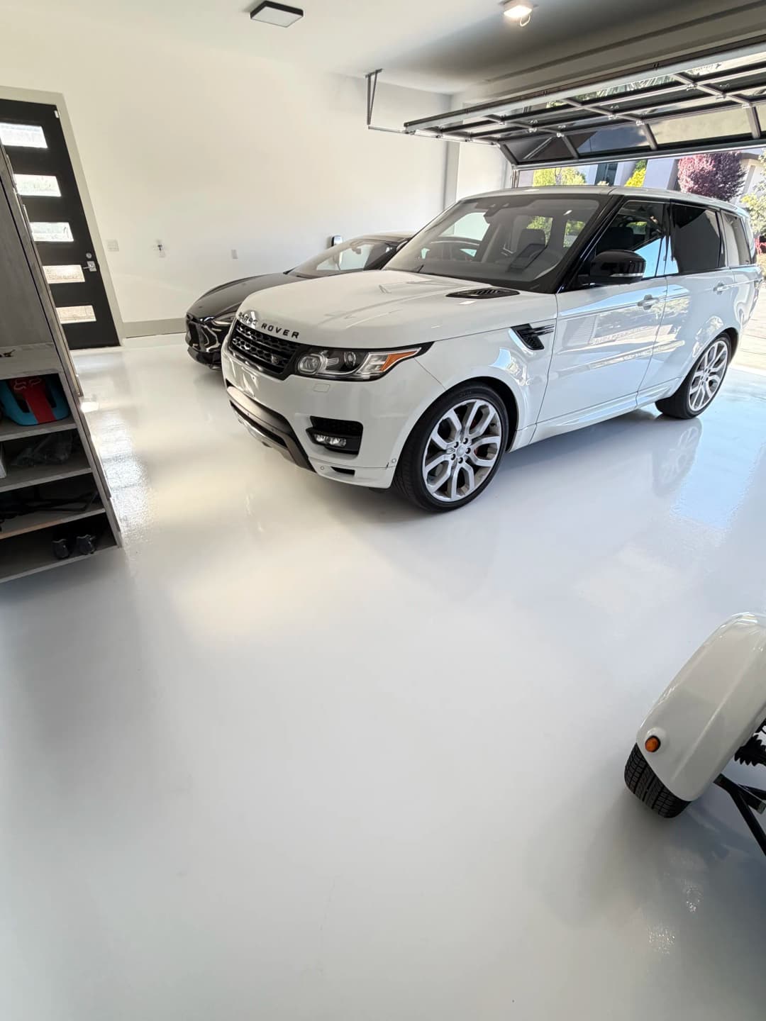 Luxury garage featuring a white SUV and a sports car on a glossy floor.