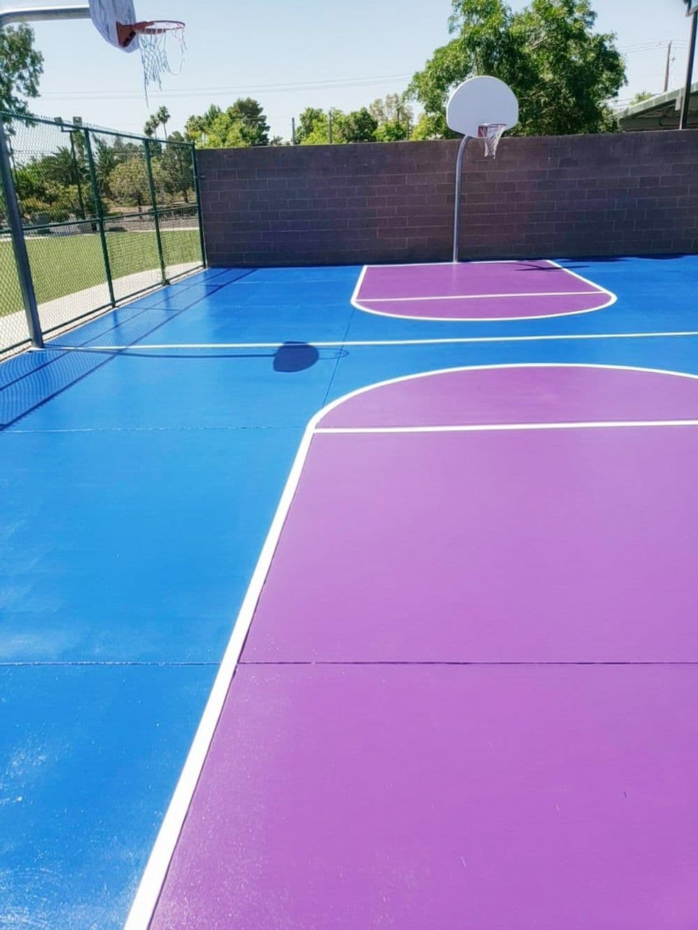 Colorful outdoor basketball court featuring blue and purple playing areas with a hoop.