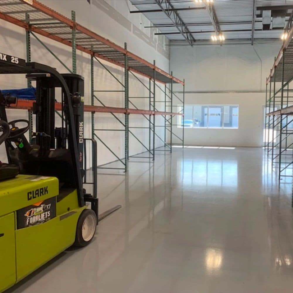 Empty warehouse interior featuring a Clark forklift and shelving units.