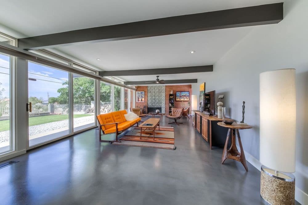 Modern living room with orange sofa, large windows, and contemporary decor.