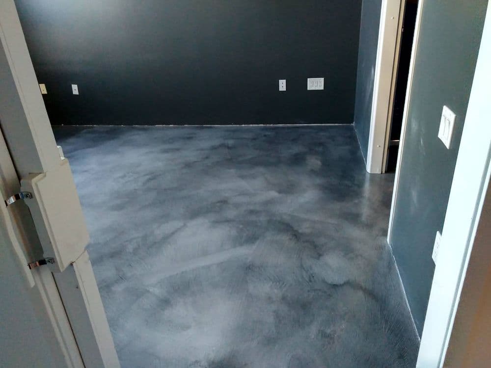 Newly finished gray concrete floor in a modern room with dark gray walls.