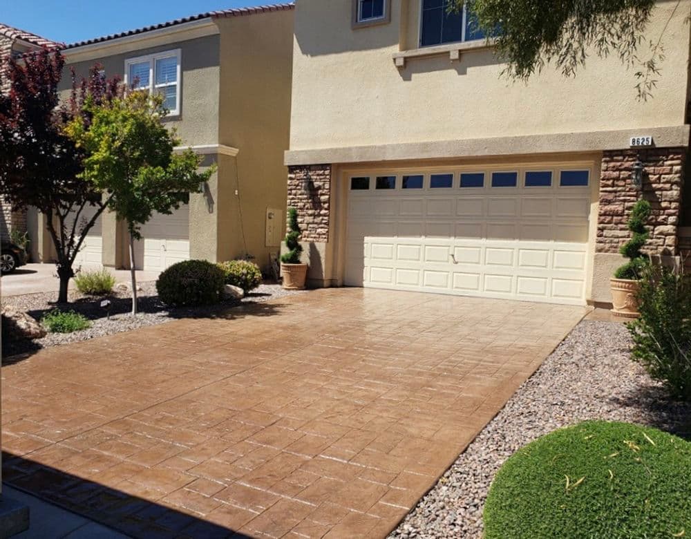 Stamped concrete driveway with a two-car garage and landscaped front yard in a suburban neighborhood.