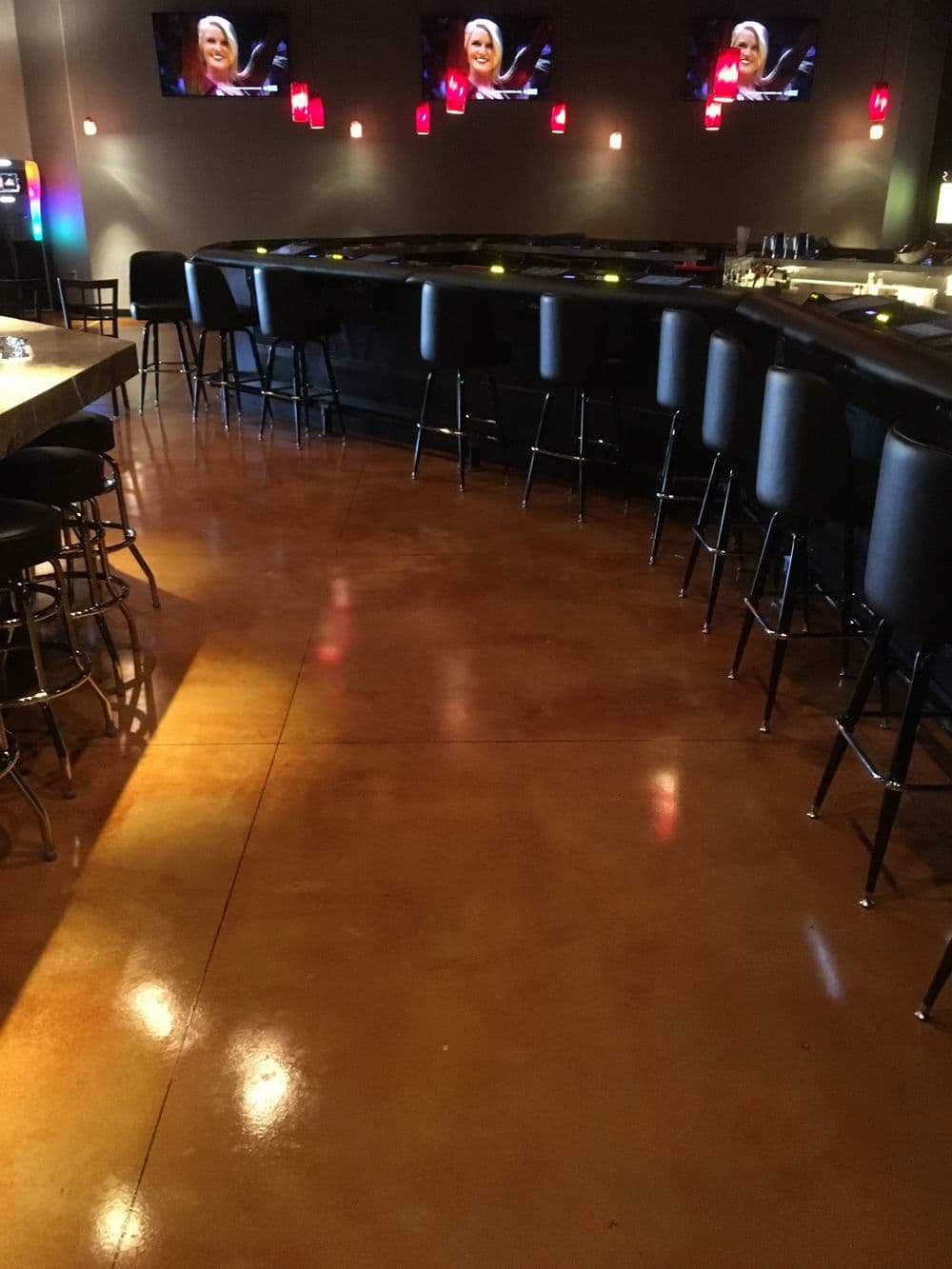 Modern bar interior featuring black stools and illuminated red pendant lights.