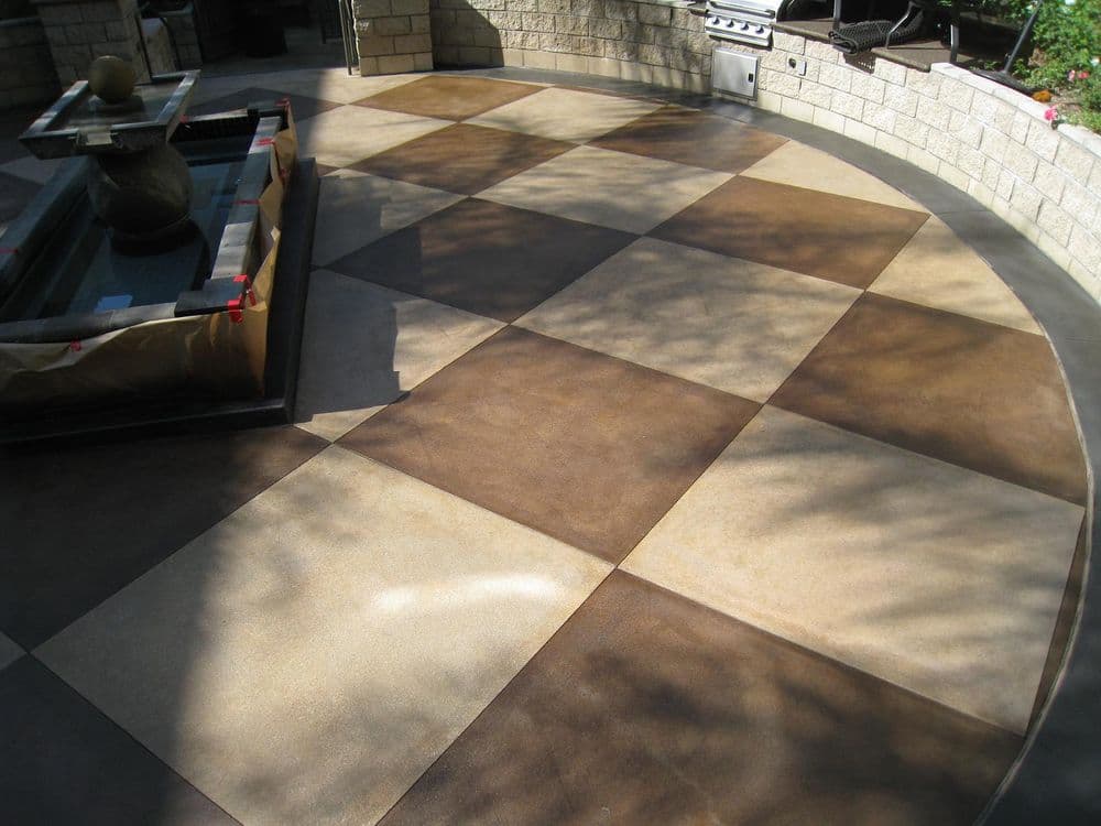 Stylish brown and beige patterned concrete patio with decorative fountain and grill area.