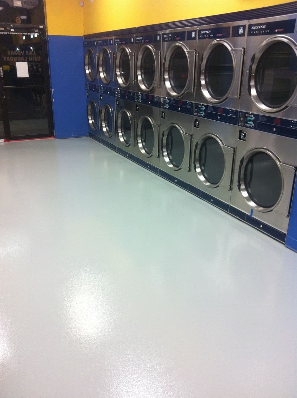 Row of shiny dryers in a bright laundry room with clean, polished floors.