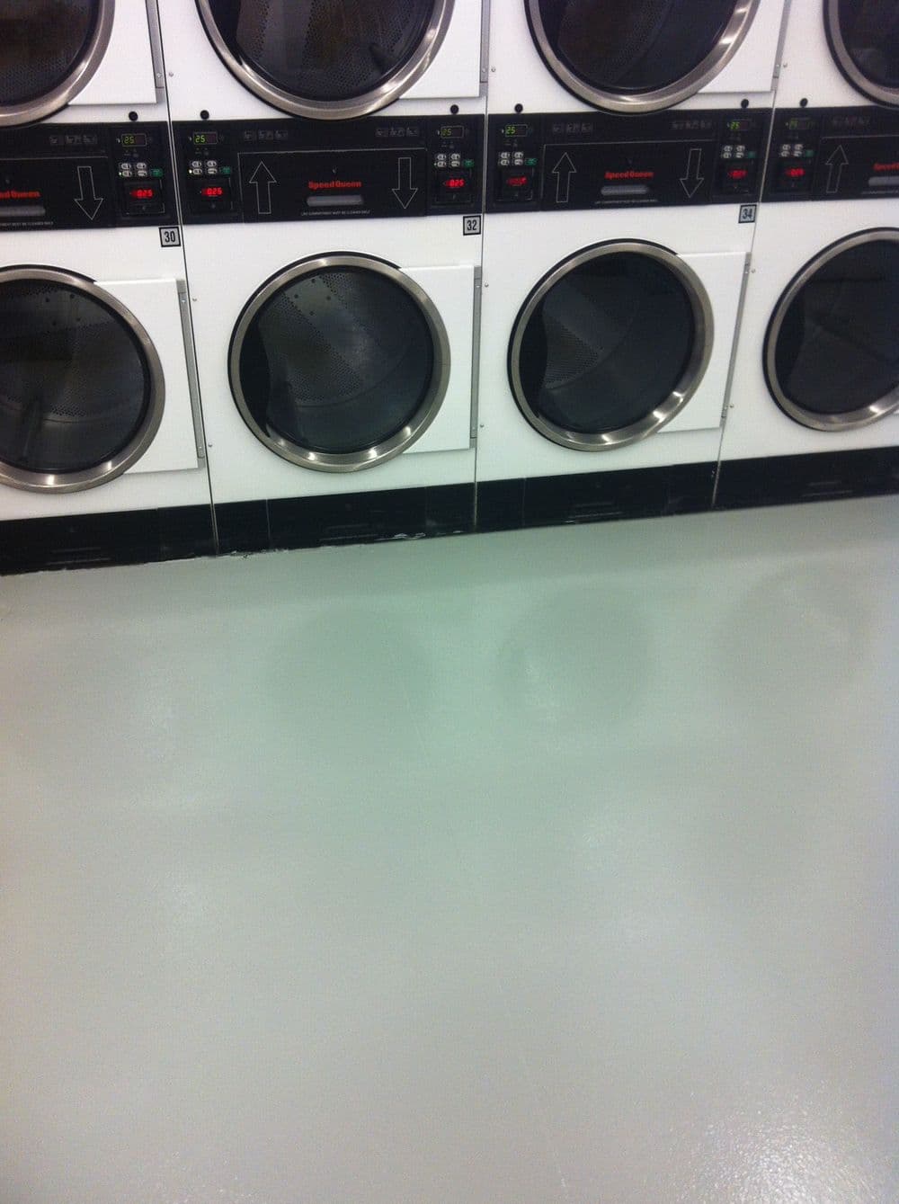 Front-loading washing machines in a laundry facility with clean, polished floors.
