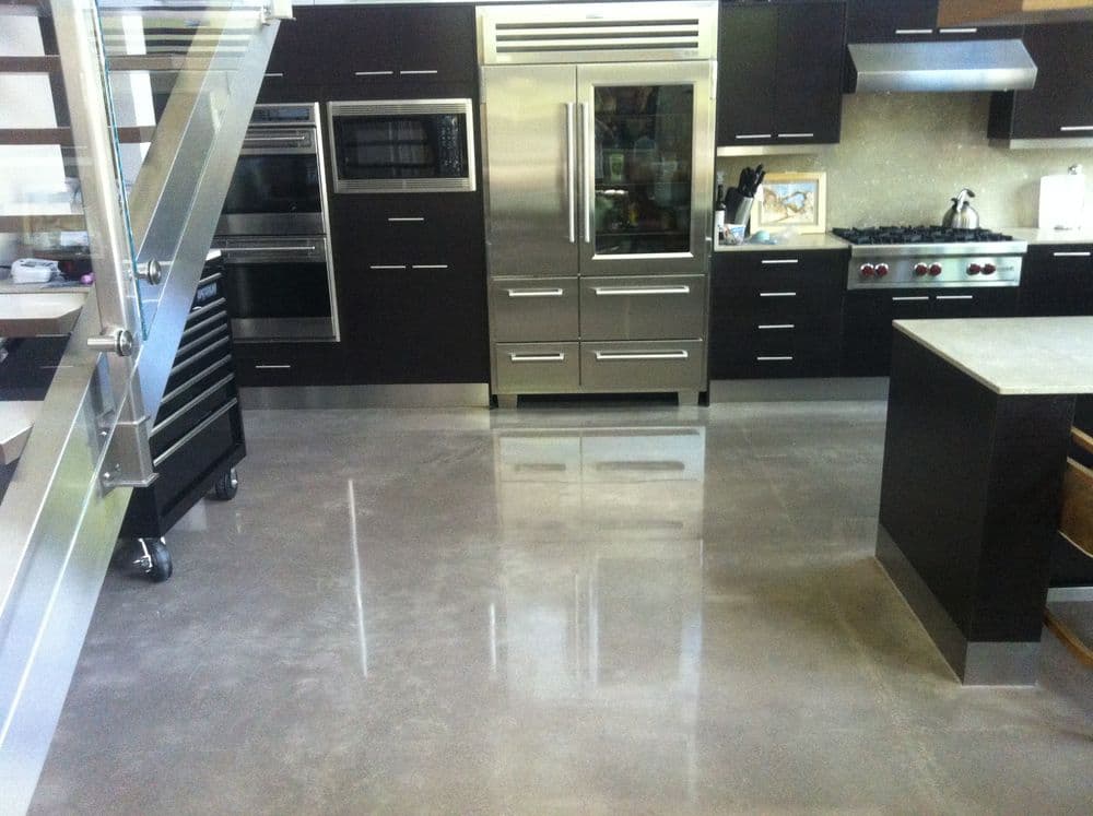 Modern kitchen with stainless steel appliances, sleek cabinetry, and polished concrete floor.