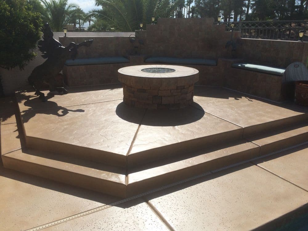 Elegant outdoor seating area with a central fire pit, palm trees, and stone decor.