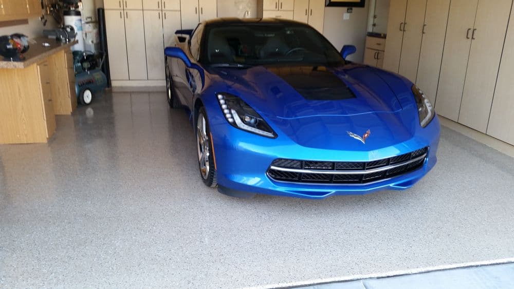 Blue Corvette sports car parked in a well-organized garage with storage cabinets.