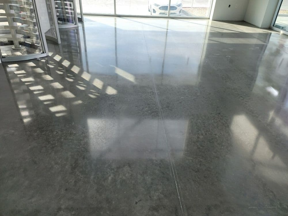 Polished concrete floor in modern interior with natural light and large windows.