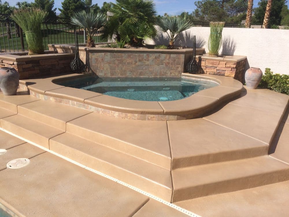 Elegant spa with stone features, surrounded by lush landscaping and steps for easy access.