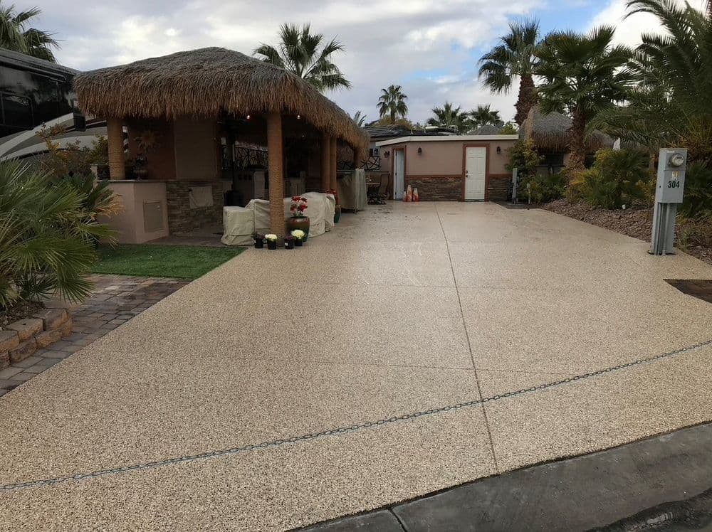 Decorative concrete driveway with tropical-themed patio and palm trees in a residential area.