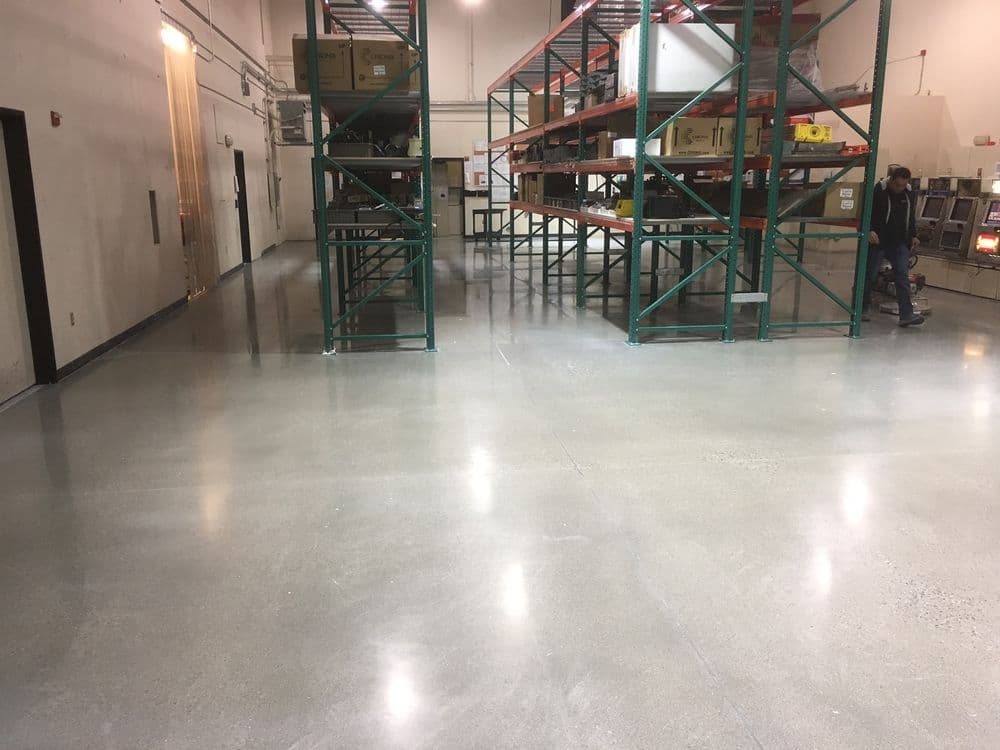 Warehouse interior with polished concrete floor and metal shelving units in the background.