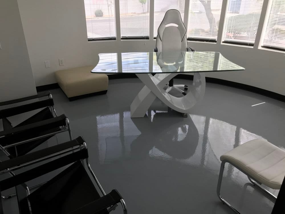 Modern office interior featuring a sleek glass desk, ergonomic chair, and minimalist seating.
