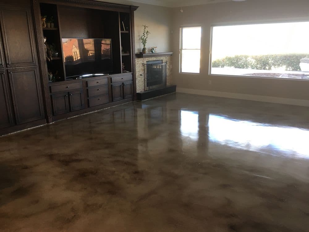 Modern living room with polished concrete floor, dark wood furniture, and large windows.