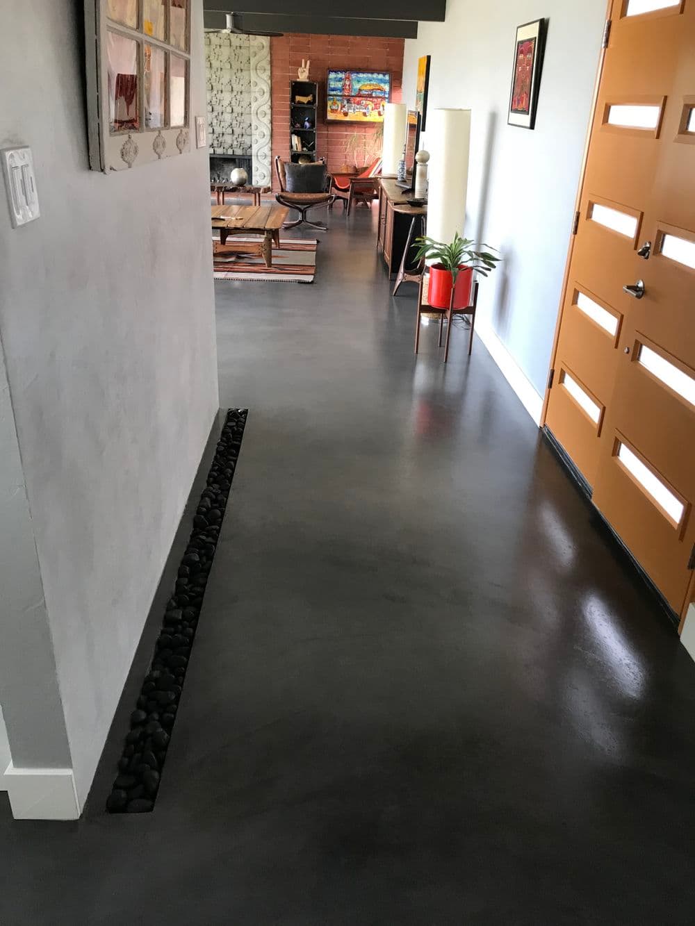 Modern interior hallway with polished concrete floor and vibrant orange door.