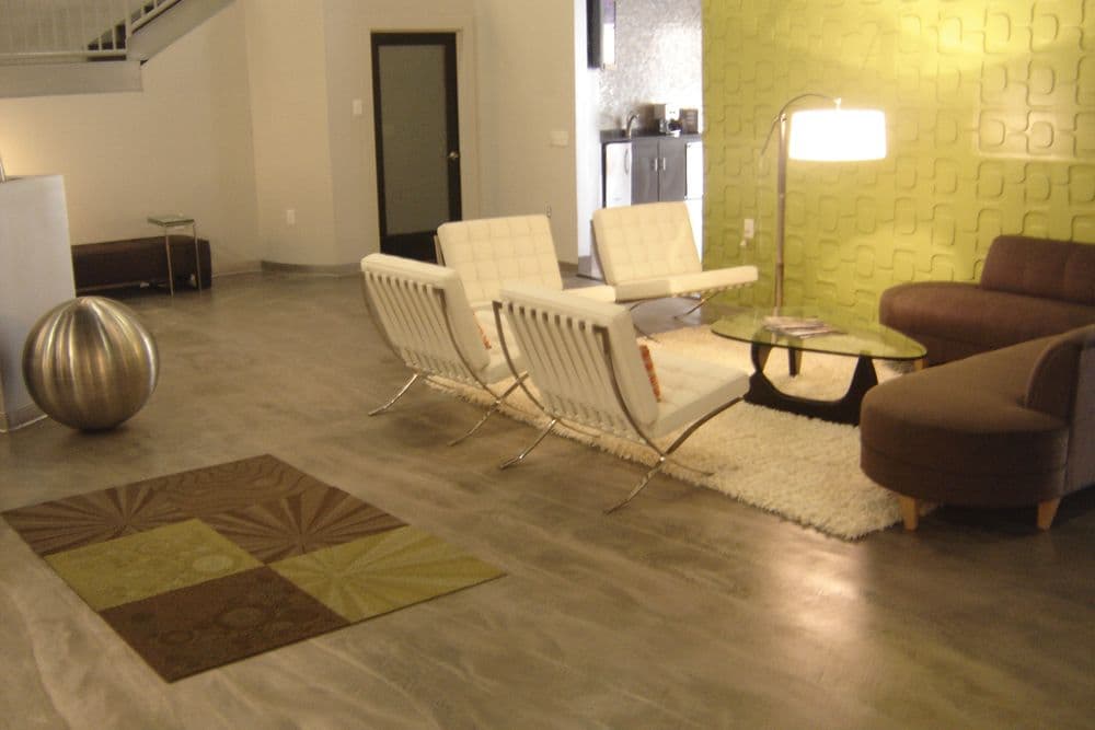 Modern living room with stylish chairs, round lamp, rug, and green accent wall.