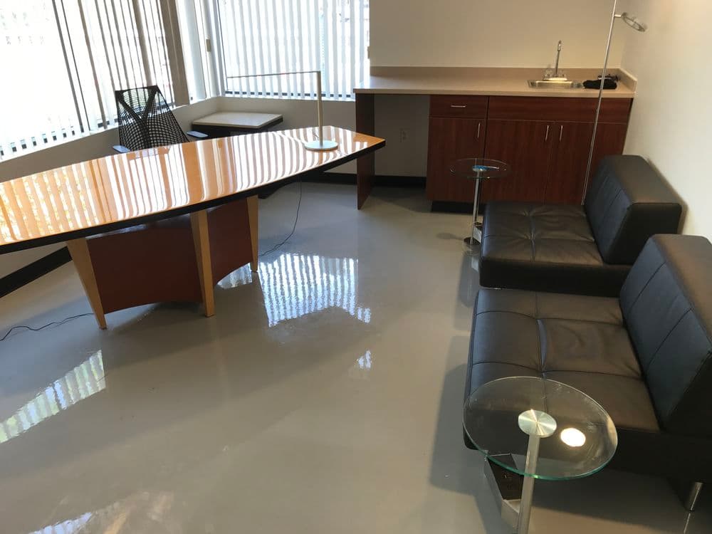 Modern office interior featuring a wooden conference table, leather sofas, and sleek side tables.