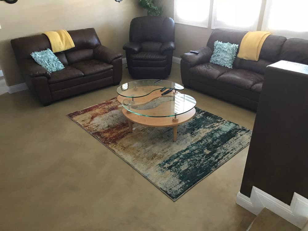 Cozy living room with brown leather sofas, a glass coffee table, and a colorful area rug.