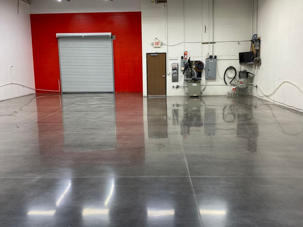 Industrial space with polished concrete floor and red accent wall, featuring a storage door.