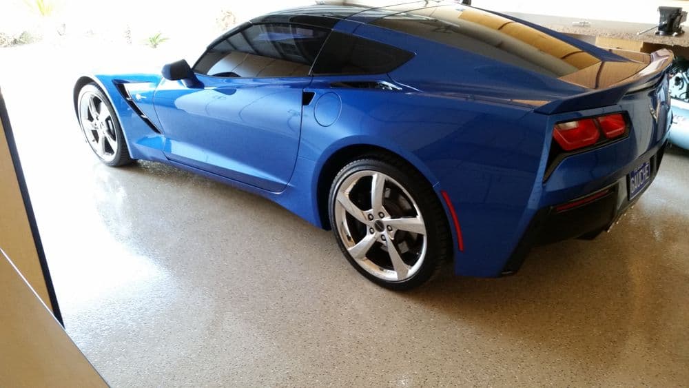 Blue Corvette C7 parked in a garage, showcasing sleek design and polished wheels.
