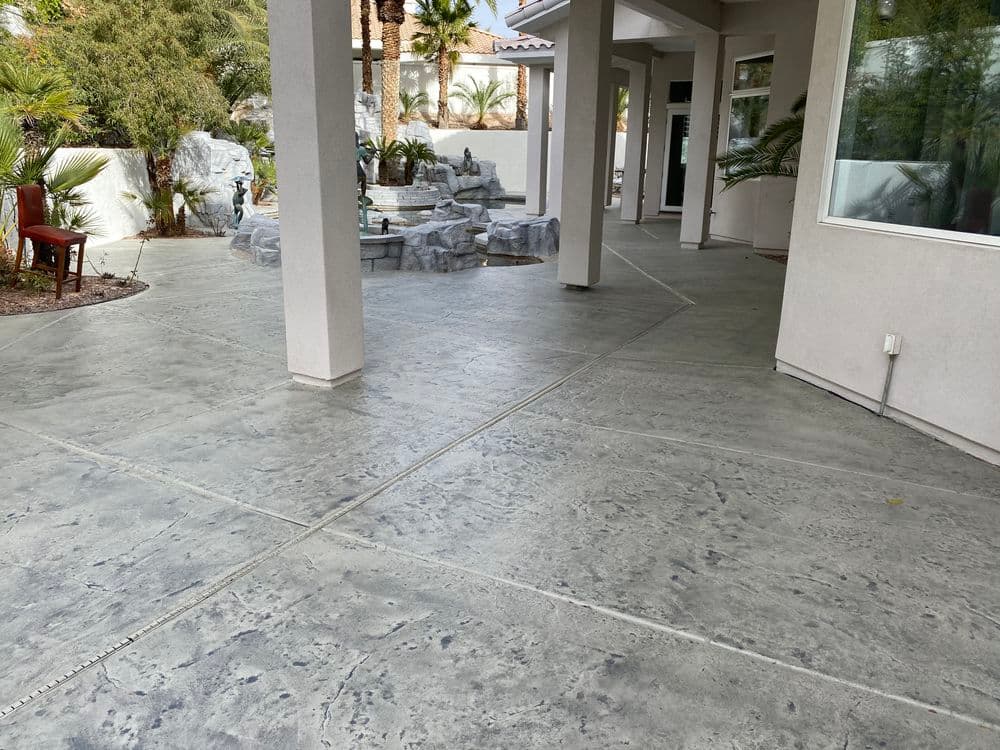 Modern concrete patio with decorative finish, surrounded by tropical landscaping and water features.