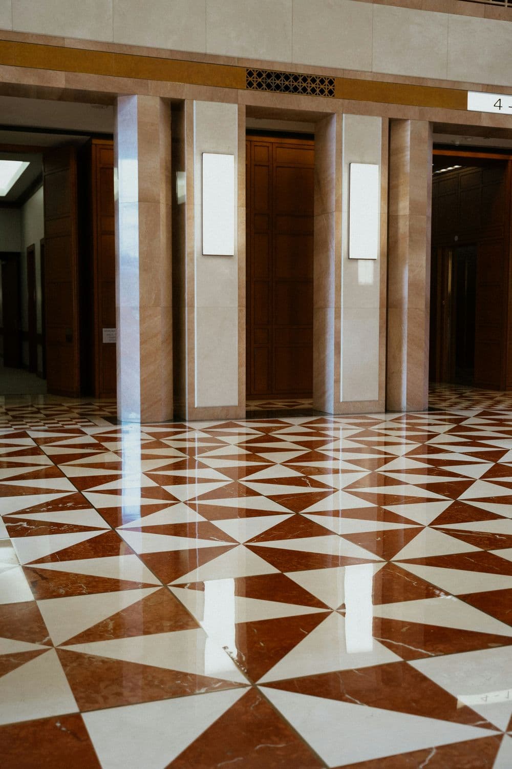 Geometric patterned floor tiles in a modern lobby with elegant lighting and polished surfaces.