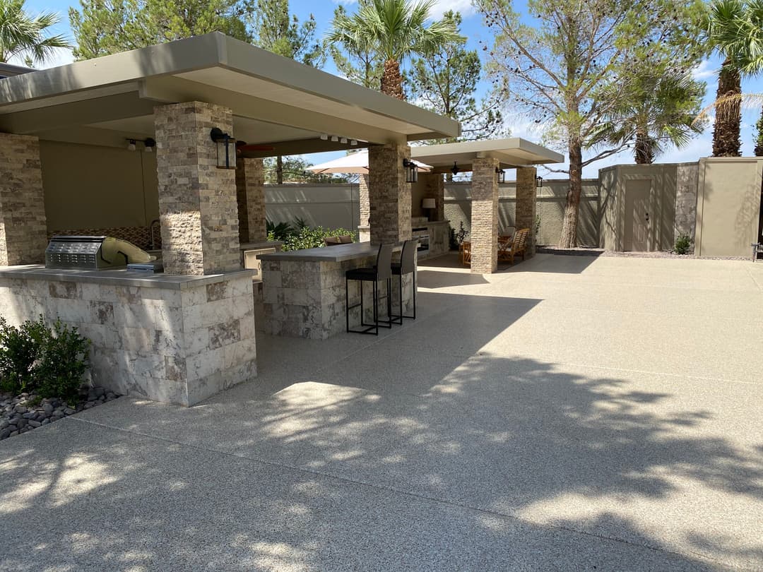 Outdoor patio area with stone columns, seating, and palm trees in a serene setting.