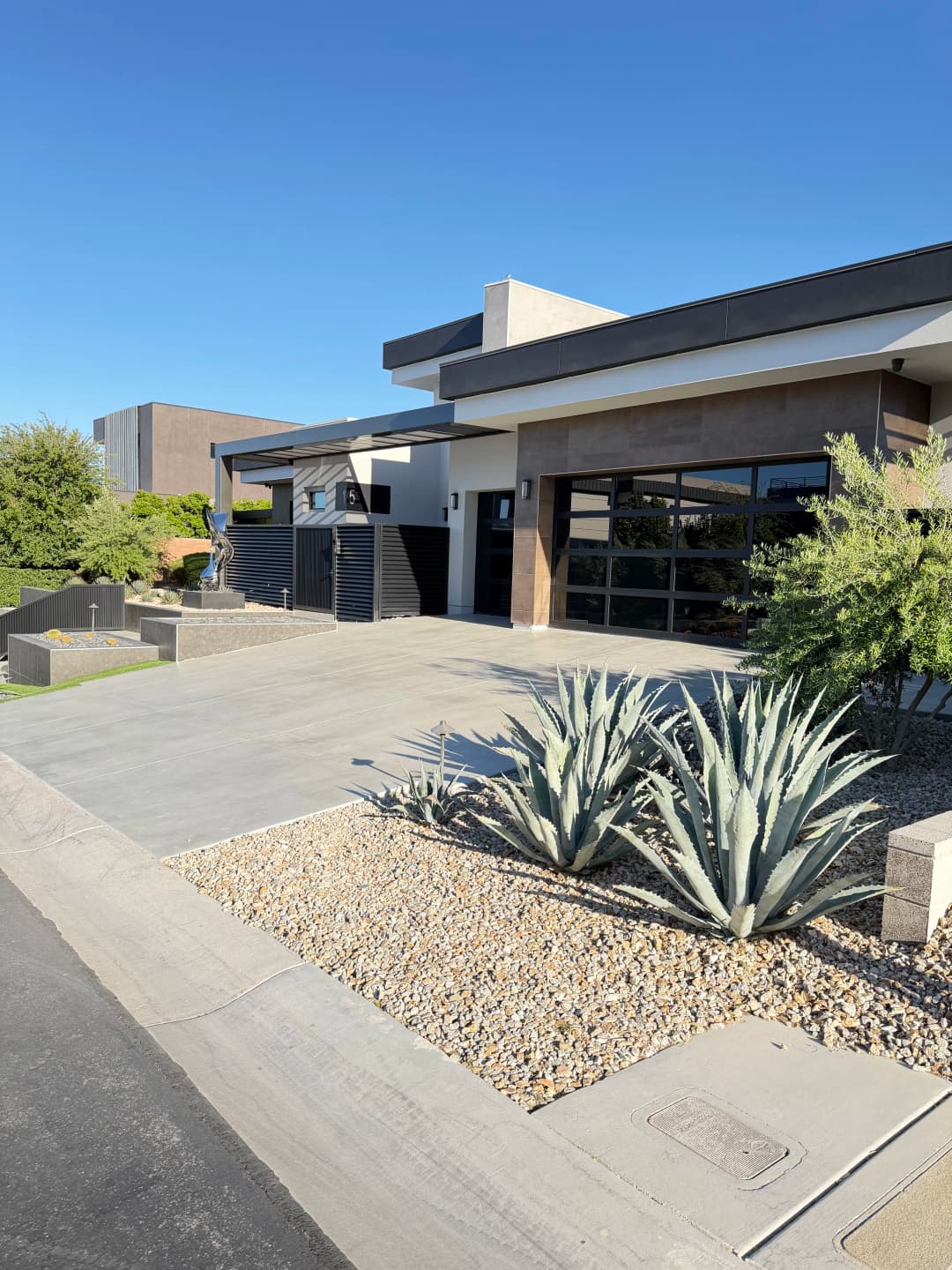 Modern home exterior with driveway, desert landscaping, and contemporary architecture.