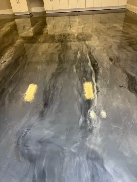 Glossy epoxy floor with a metallic swirl design in a modern garage setting.