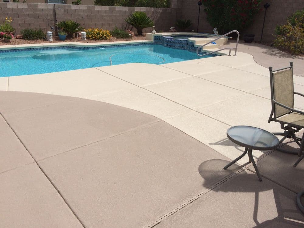 Residential backyard pool with seating area, landscaped gardens, and a hot tub.